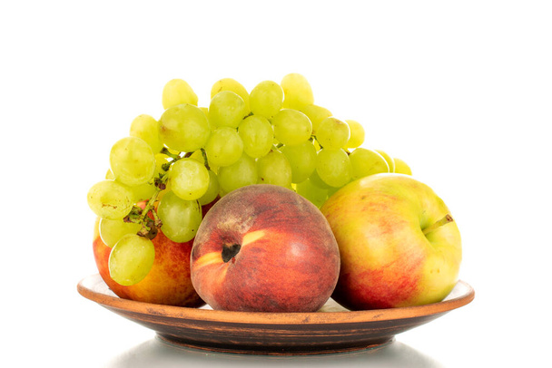 Одна група білого винограду Quiche mis, яблуко, персик і нектар на керамічній тарілці, крупним планом, ізольовані на білому тлі
. - Фото, зображення