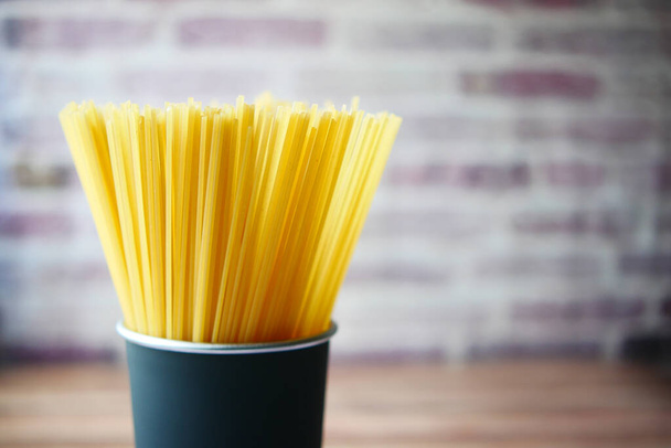 Жовтий довгий спагетті в контейнері на столі
 , - Фото, зображення