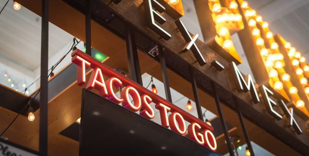 Ресторан "Текс Мекс" вітає підпис з LED Tacos, щоб відправити текст в Техасі, Америка. Погляд на великий Тако бере текст у сучасній їдальні аеропорту.. - Фото, зображення