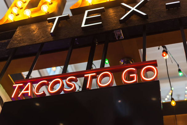 Colorful light bulb and red LED Tacos to go text at Tex Mex restaurant in Texas, America. Lookup view of large Taco take away text at modern airport restaurant. - Fotoğraf, Görsel