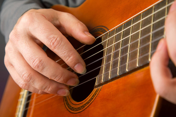 man plays the classical guitar. string musical instrument. hands of the musician playing on classical guitar - Foto, afbeelding
