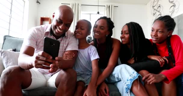 Black family taking selfie together, african parents and children using smartphone laughing and smiling - Materiał filmowy, wideo