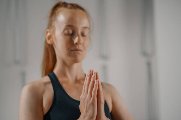 Close-up of a woman doing Pilates yoga stretching in studio. Hands folded in namaste - Valokuva, kuva