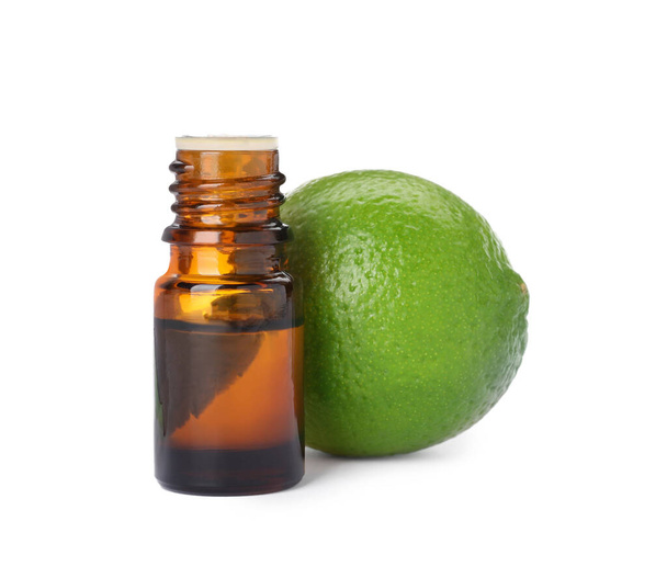Bottle of citrus essential oil and fresh lime isolated on white - 写真・画像