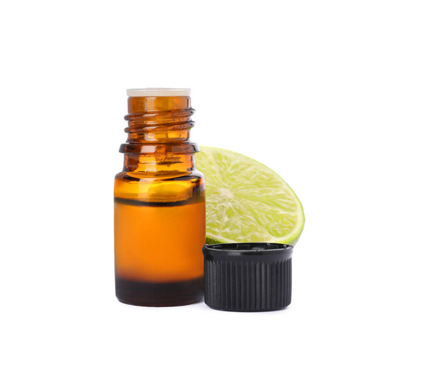Bottle of citrus essential oil and cut fresh lime isolated on white - Photo, Image