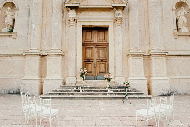 Pedestals with flowers stand on the steps of the Church of the Nativity of the Virgin in Prcanj. High quality photo - Foto, Imagem