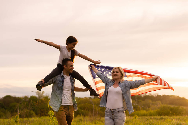 Bir tarlada Amerikan bayrağı taşıyan aile - Fotoğraf, Görsel