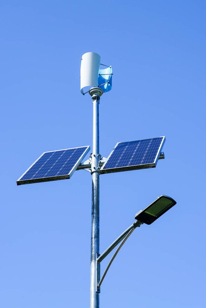 Pole with innovative LED street light powered by solar cells and small vertical wind generator, blue sky background - Foto, immagini
