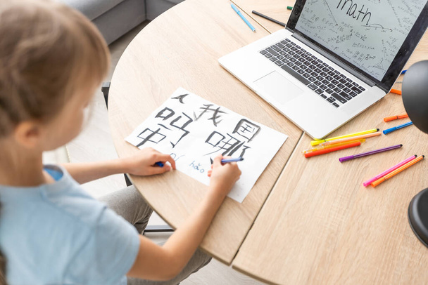 menina aprendendo chinês ao usar seu computador portátil na sala de estar em casa. conceito de actividade familiar - Foto, Imagem