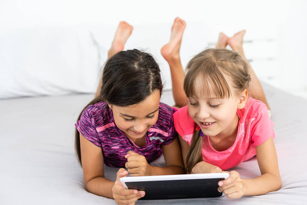 mensen en kinderen, technologie, vrienden, vriendschap concept - meisjes op zoek naar tablet pc-computers thuis. - Foto, afbeelding