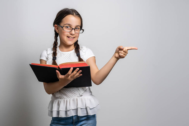 Bruneta holčička čtení knihy izolované na více než bílém pozadí. - Fotografie, Obrázek