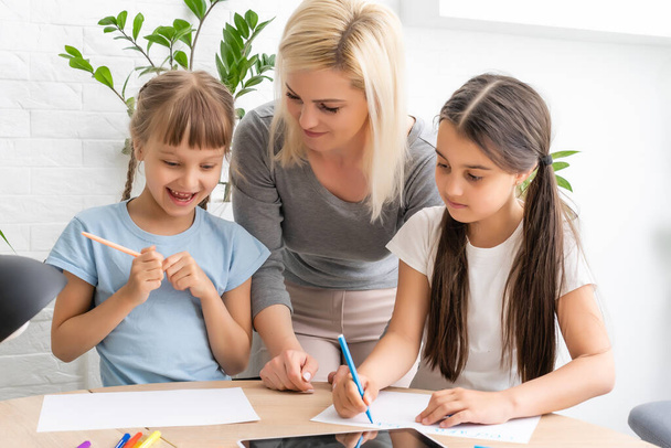 Bella giovane madre che aiuta le sue figlie con i compiti - Foto, immagini