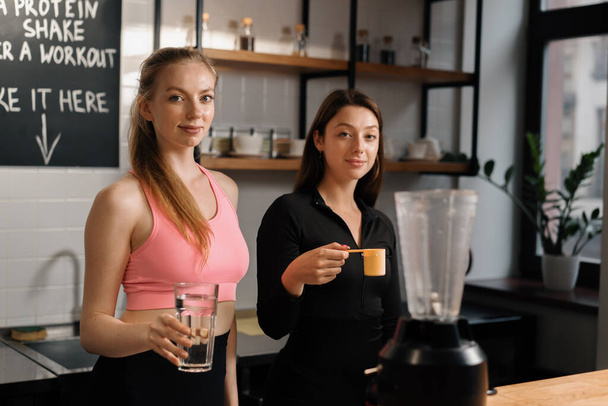 Two curvy women make a protein shake at the fitness health bar in gym - Valokuva, kuva