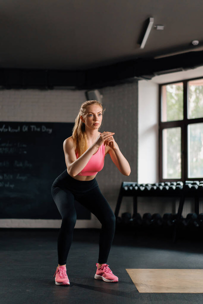 Athletic woman doing squat workout exercise in the gym - Valokuva, kuva