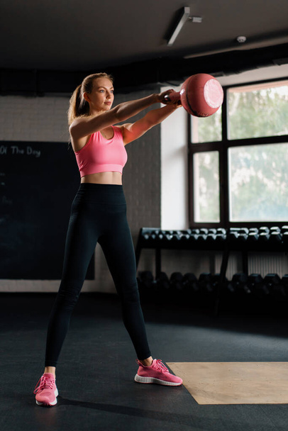 Athletic woman doing squat mobility workout exercise with kettlebell. - 写真・画像