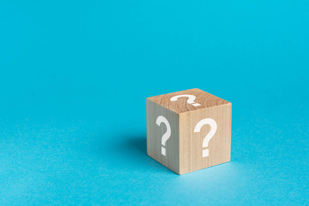 φυσικό ξύλινο κύβο με ερωτήσεις λευκά σημάδια, φωτεινό μπλε φόντο - Φωτογραφία, εικόνα