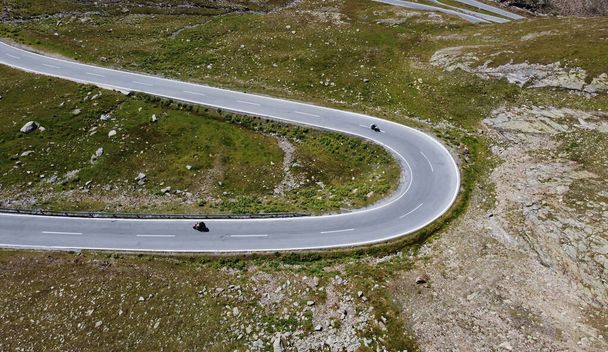 Aerial drone shot of tight curve with motorcyclist in mountains - Foto, Bild