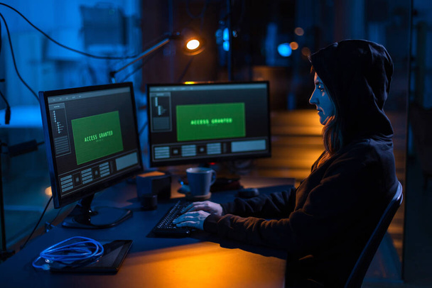 cybercrime, hacking and technology concept - female hacker in dark room breaking security system or using computer virus program for cyber attack - Photo, image