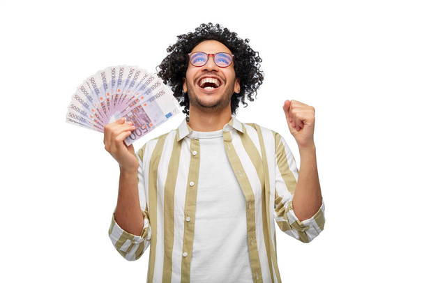 finance, currency and people concept - happy man holding hundreds of euro money banknotes celebrating success over white background - Fotoğraf, Görsel