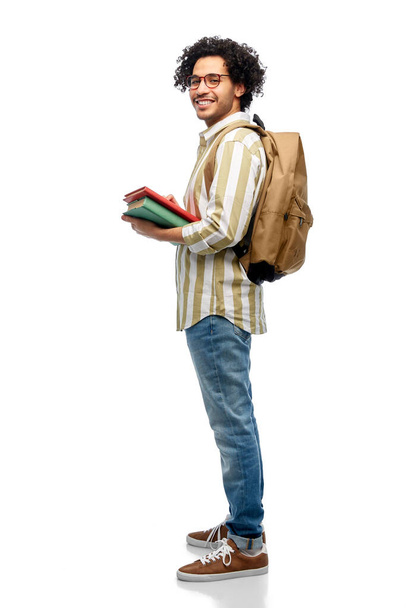 people and education concept - happy smiling man in glasses with backpack and books over white background - Foto, Bild