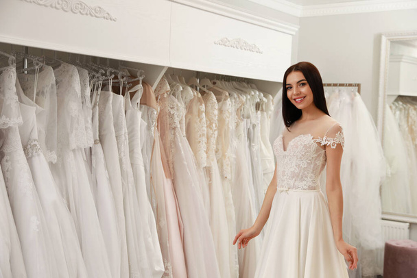 Woman trying on beautiful wedding dress in boutique - 写真・画像