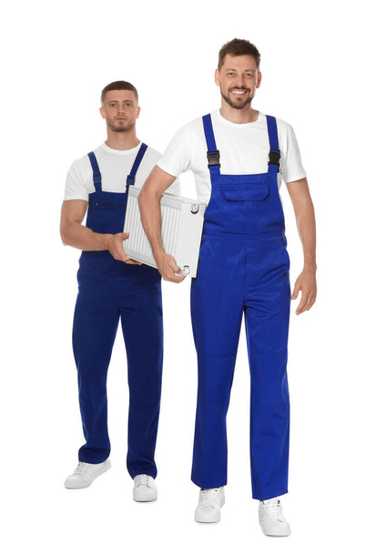 Professional plumbers with new heating radiator on white background - Foto, afbeelding