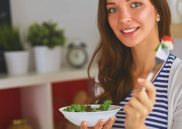 Young woman eating salad and holding a mixed salad . - 写真・画像