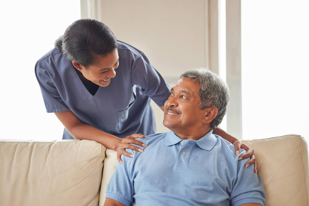 Healthcare, support and nurse working in senior care, bonding with patient showing affection in retirement home. Happy health care worker smiling, caring for mature man in an assisted living facility. - Foto, afbeelding