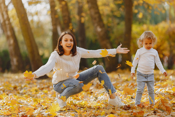Fashionable mother with daughter. Family in a autumn park. Little girl in a white sweater. - Foto, Imagen