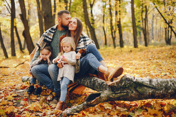 Family in a autumn park. Woman in a red sweater. Cute childrens with parents - Фото, зображення