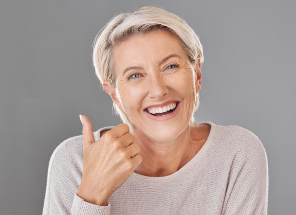 Skincare, wellness and thumbs up by happy mature woman smiling showing winning hand gesture against studio background. Senior support and recommend cosmetic surgery, treatment or product for wrinkles. - Zdjęcie, obraz