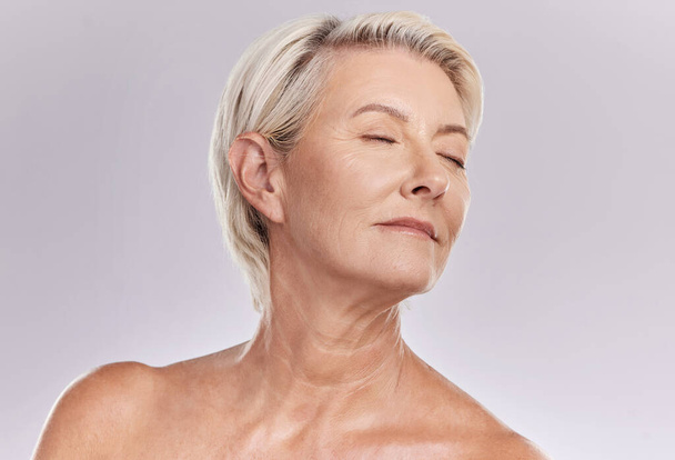 Beauty, skincare and face of a senior woman posing with closed eyes and topless against grey studio background. Happy old, elderly or mature female with glowing skin due to cosmetic self care. - Photo, image