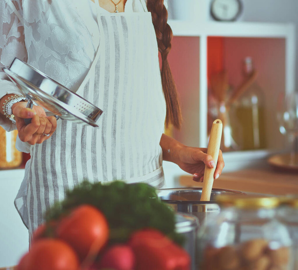 Cooking woman in kitchen with wooden spoon. - Foto, Bild