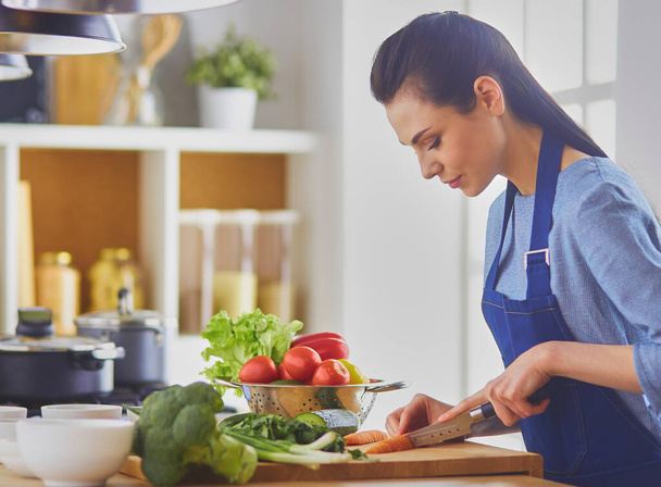 Giovane donna che taglia verdure in cucina a casa. - Foto, immagini