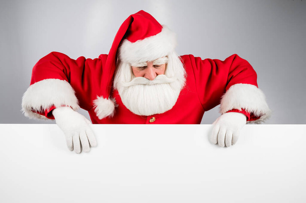 Santa Claus peeks out from behind an ad on a white background. Merry Christmas - Fotó, kép