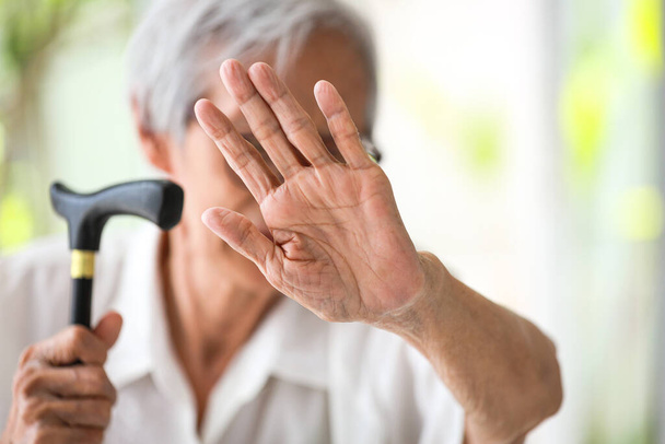 Azjatycka seniorka wykonująca gest zatrzymania palmą, przeciwko przemocy domowej, starsi ludzie podnoszący rękę, aby pokazać znak, przestać znęcać się nad osobami starszymi, krzywdy fizyczne, uszkodzenia psychiczne, znęcanie się, złe traktowanie - Zdjęcie, obraz