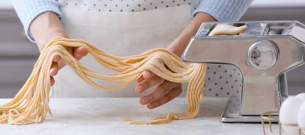 Woman making pasta with machine in kitchen, closeup - Foto, imagen
