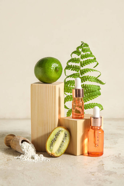 Composition with bottles of essential oil, kiwi, lime and fern leaf on light background - Foto, imagen