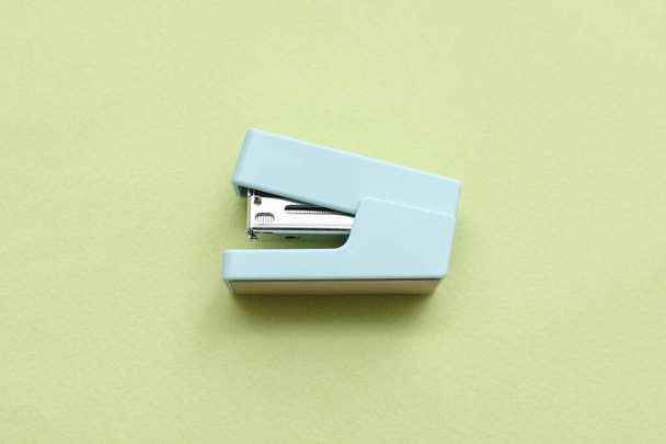 Blue stapler on green background - Valokuva, kuva