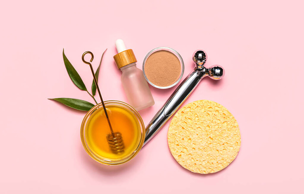 Facial massage tool with cosmetic products, honey and leaves on pink background - Fotoğraf, Görsel