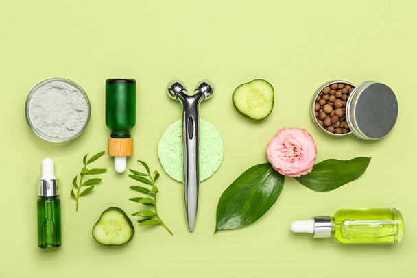 Facial massage tool with cosmetic dropper bottle and components on green background - Foto, Imagen