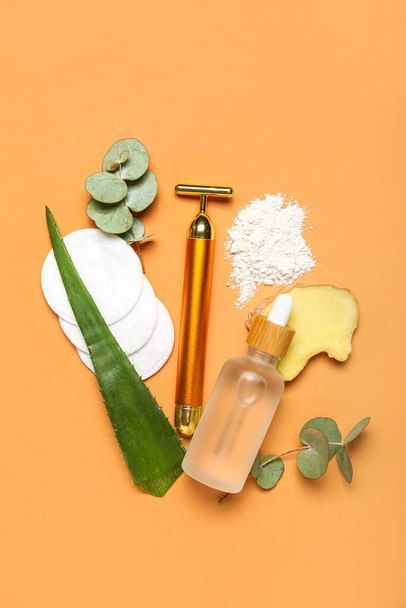 Facial massage tool with cosmetic bottle, cotton pads and components on beige background - 写真・画像