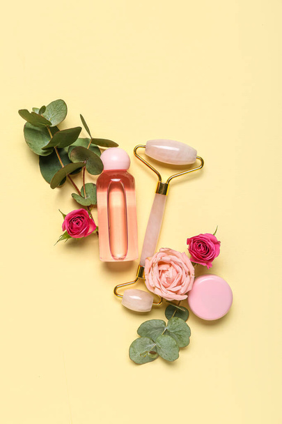 Facial massage tool with cosmetic products, flowers and eucalyptus on beige background - Foto, Imagem
