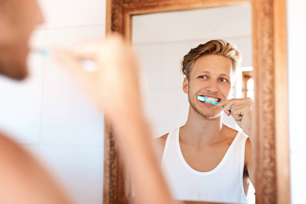 Theyre gonna shine so bright. a young man brushing his teeth at home - Fotó, kép