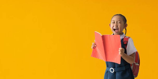 Funny smiling child school girl with hold books, isolated on yellow background with Clipping paths for design work empty free space - Photo, image