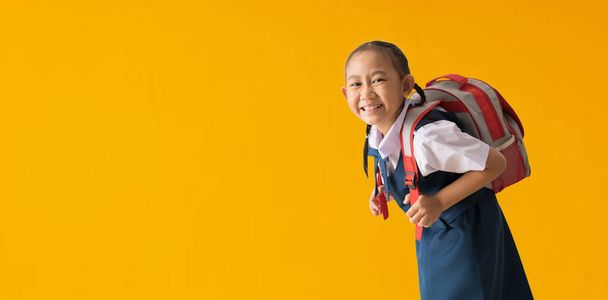 Funny cute smiling schoolgirl in uniform, isolated on yellow background with Clipping paths for design work empty free space - Foto, afbeelding