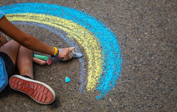 A child draws a rainbow on the asphalt. Selective focus. kid. - Photo, Image