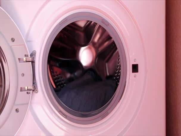 Men's hands load clothes, wardrobe into the washing machine, washing it at home. Daily life, housework. - Materiaali, video