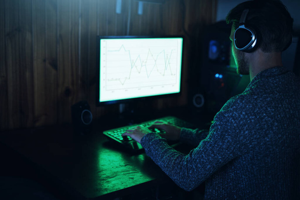 Just breached down a firewall. a young man using a computer and hacking in a dark room at home - 写真・画像