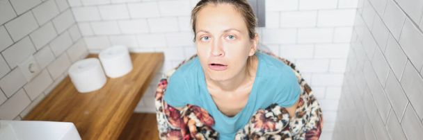 Junge Frau auf Toilette sitzend und grimmig. Behandlungskonzept für Durchfall - Foto, Bild